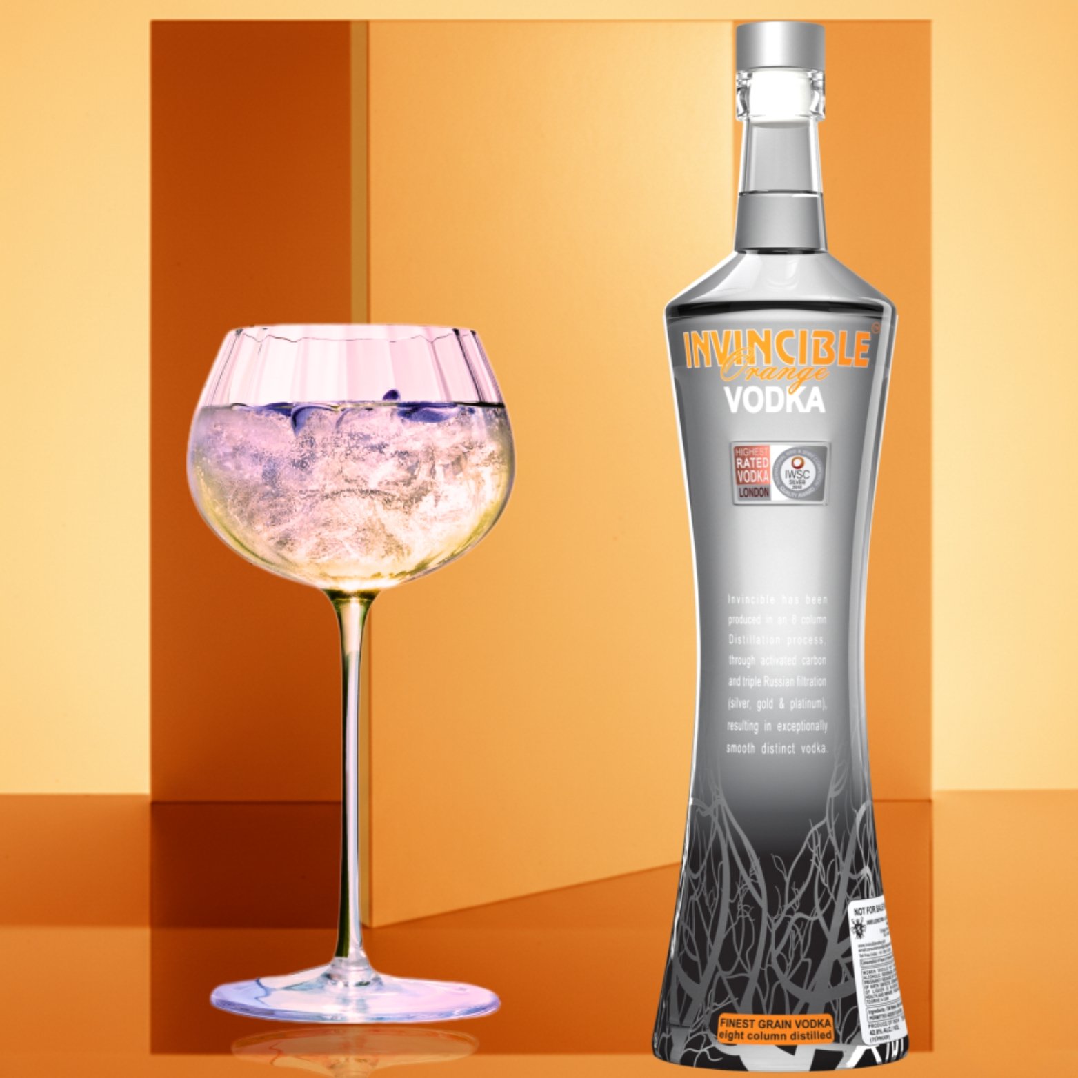 Invincible Vodka Orange Flavour bottle displayed beside an ice-filled cocktail glass on a modern blue background, highlighting a refreshing vodka serve.