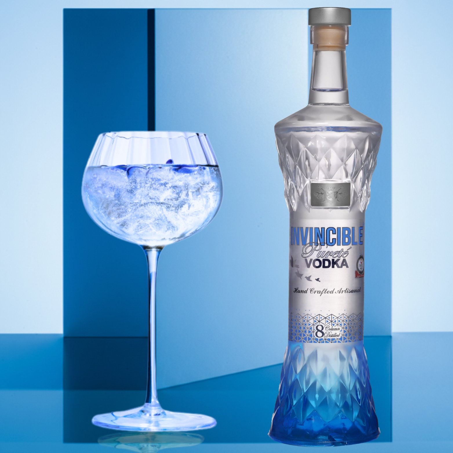Premium Invincible Vodka bottle displayed beside an ice-filled cocktail glass on a modern blue background, highlighting a refreshing vodka serve.