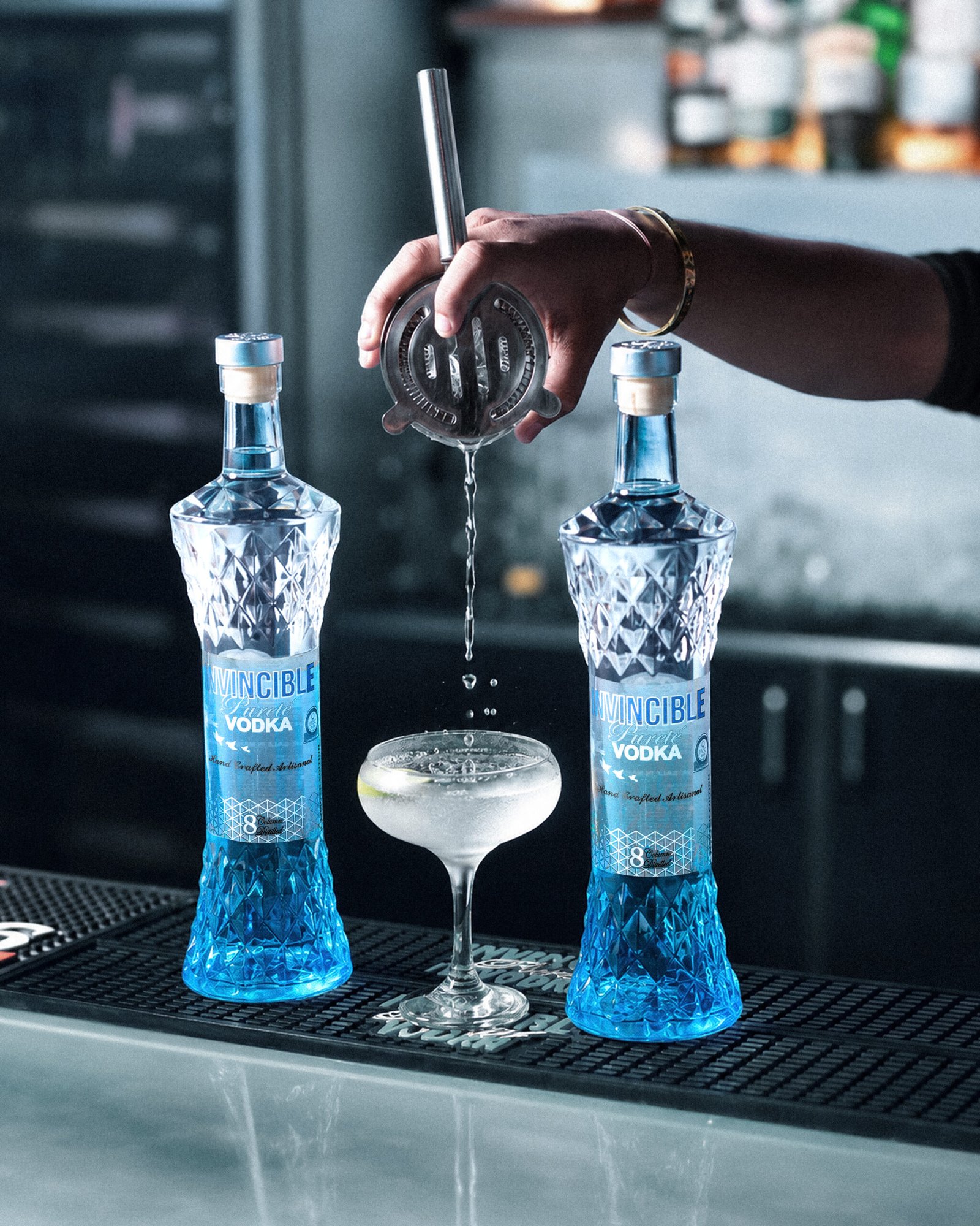 Two invincible vodka bottles placed on bar mat with cocktail in the center